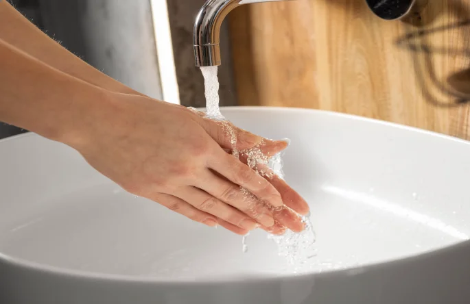 Person washing hands in bathroom sink
